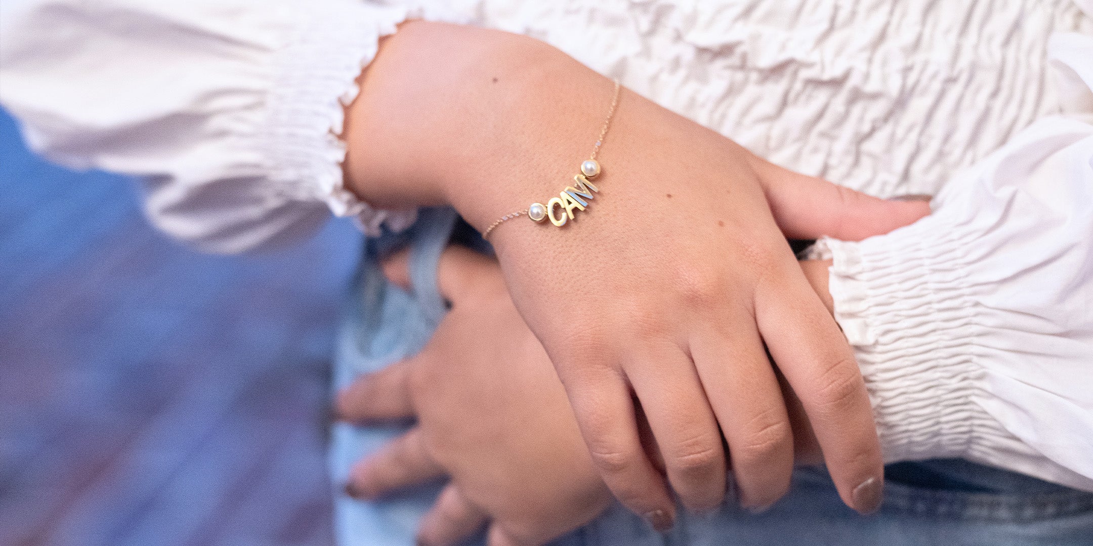 gold charm bracelet spelling "CAM" with birthstones