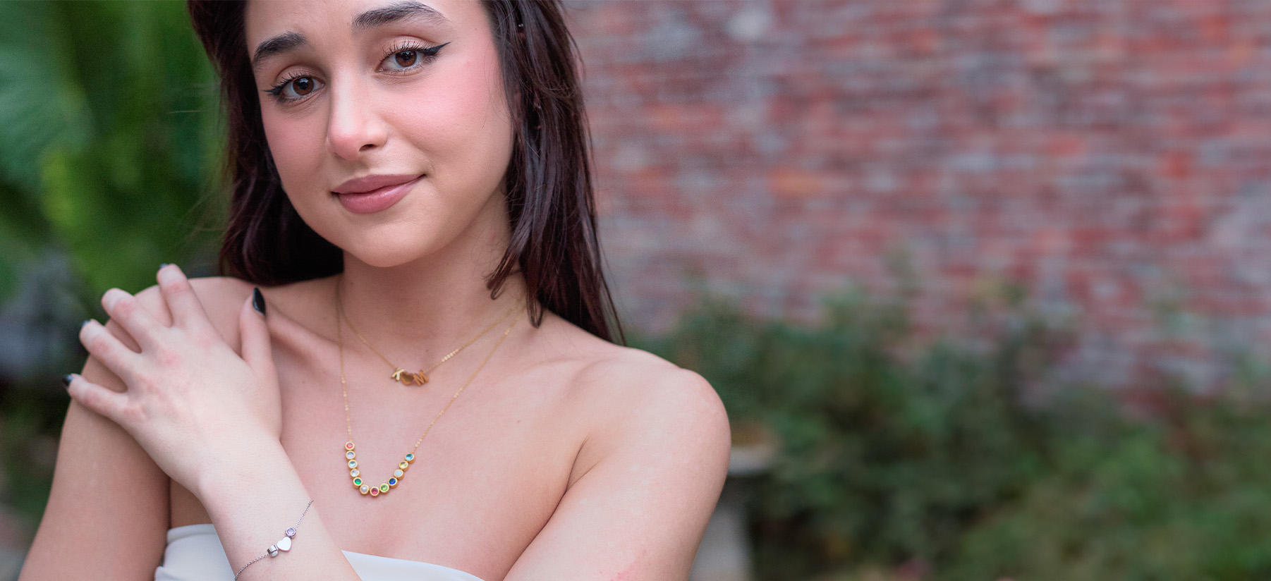 woman wearing gold charm necklace and silver charm bracelet