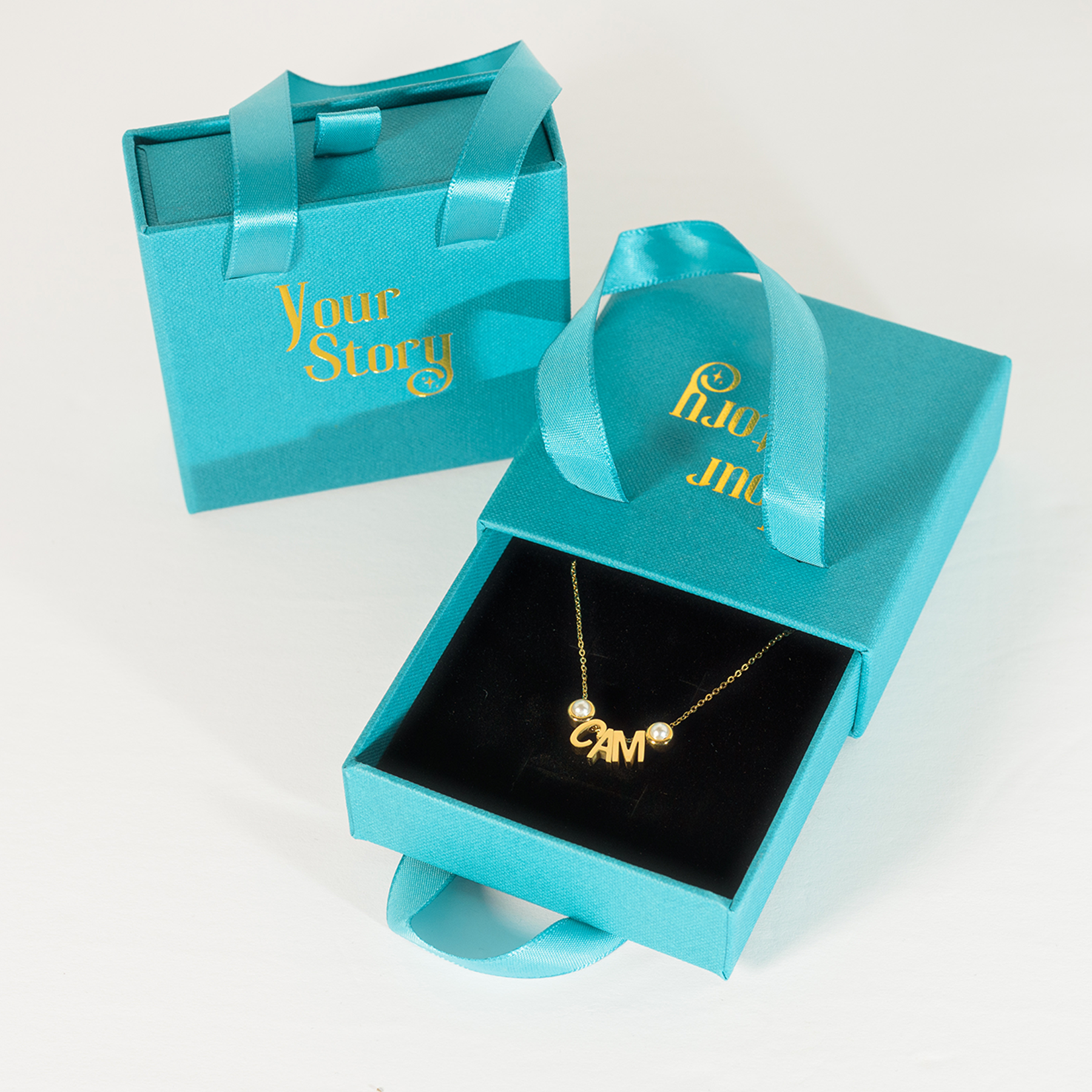 blue "your story" brand box with a gold charm necklace