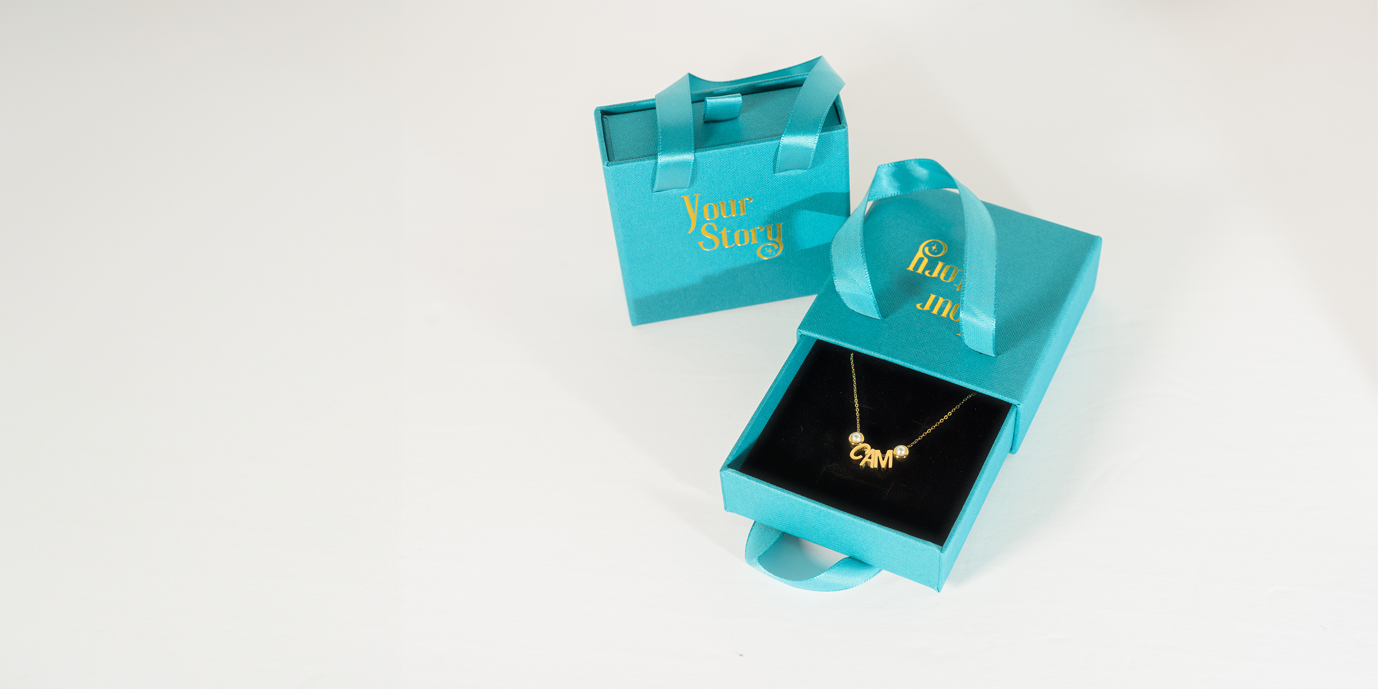 blue "your story" brand box with a gold charm necklace