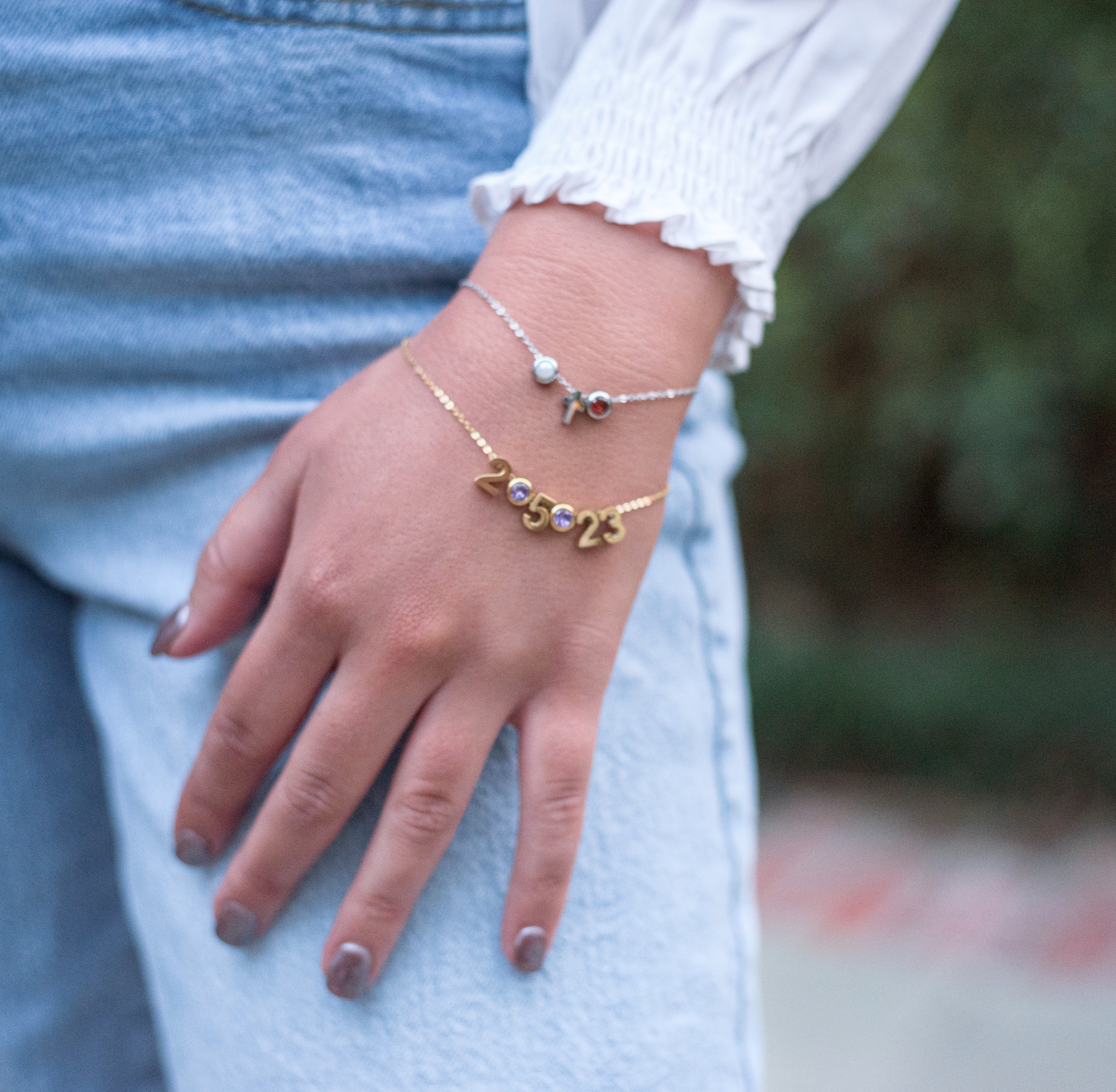 gold charm bracelet with important date and silver charm bracelet with a cross