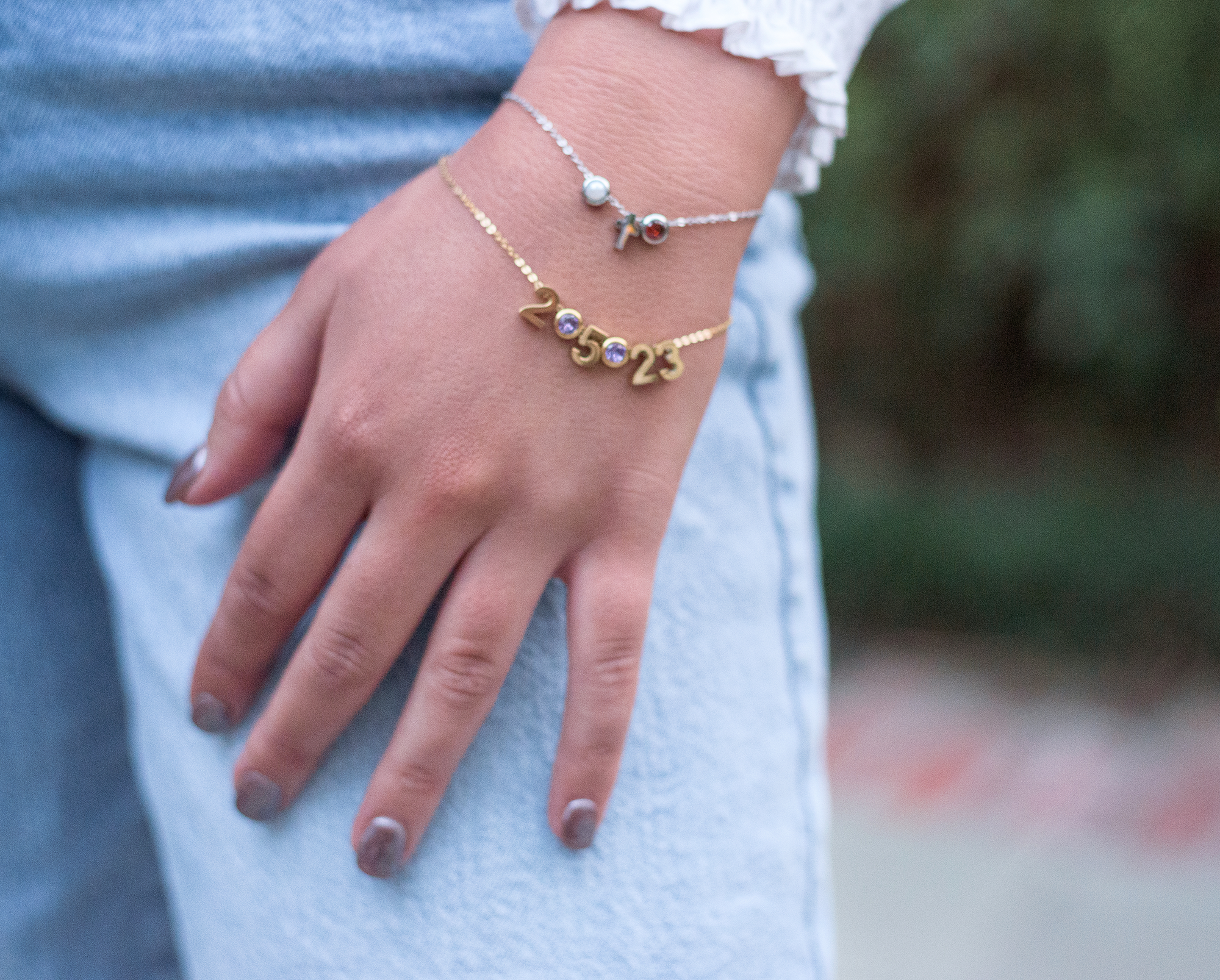 woman's hand wearing a silver and gold charm bracelet